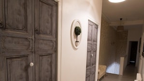 Een hal met houten deuren, een hanglamp en een kleine potplant.
