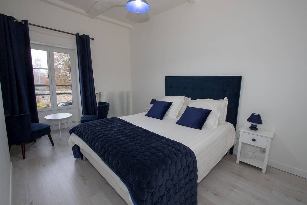 Un dormitorio moderno con una cama grande, una mesita de noche, una silla y una pequeña mesa.