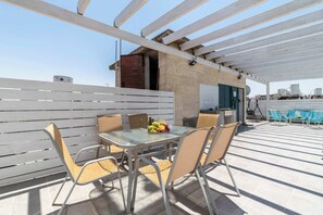 An outdoor patio with a table and chairs, a pergola, and a view of the cityscape. - HaHavatselet 19  - Isrentals (Jerusalem)