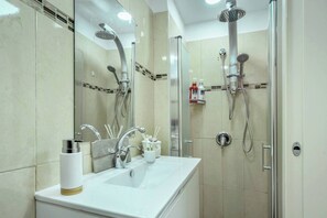 A modern bathroom with a large mirror, a sink, and two showerheads. - HaHavatselet 19  - Isrentals (Jerusalem)