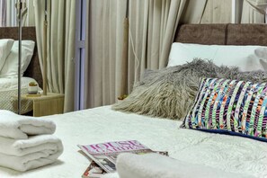 A neatly made bed with a magazine, a fluffy pillow, and a colorful pillow. - HaHavatselet 19  - Isrentals (Jerusalem)
