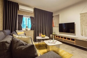 A modern living room with a sofa, coffee table, and TV. - HaHavatselet 19  - Isrentals (Jerusalem)