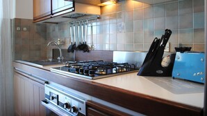 Une cuisine équipée d’une cuisinière à gaz, d’un four et d’ustensiles de cuisine suspendus.