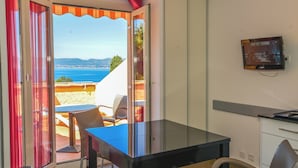 A room with a glass door leading to an outdoor area with a table and chairs, a television mounted on the wall, and a cabinet. - VVF Résidence Saint-Cyr-sur-Mer (Saint-Cyr-sur-Mer)