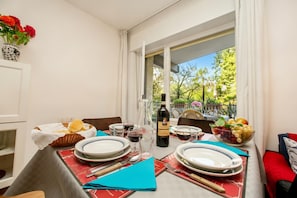Une table à manger dressée avec des assiettes, des verres, une bouteille de vin et un saladier de fruits.