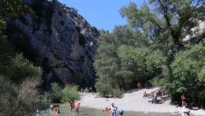 A natural outdoor setting with a river, rocky cliffs, and trees. - Village Vacances La Fontaine d'Annibal (Buis-les-Baronnies)