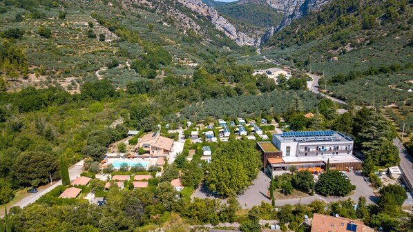 An aerial view of a resort with multiple buildings, a swimming pool, and surrounding greenery.