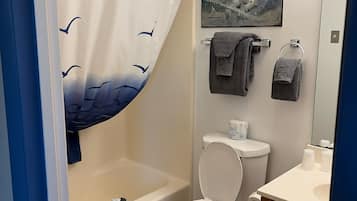 Un baño con cortina de ducha, inodoro, bañera, lavabo y toallero.