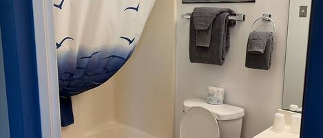 A bathroom with a shower curtain, a toilet, a bathtub, a sink, and a towel rack.