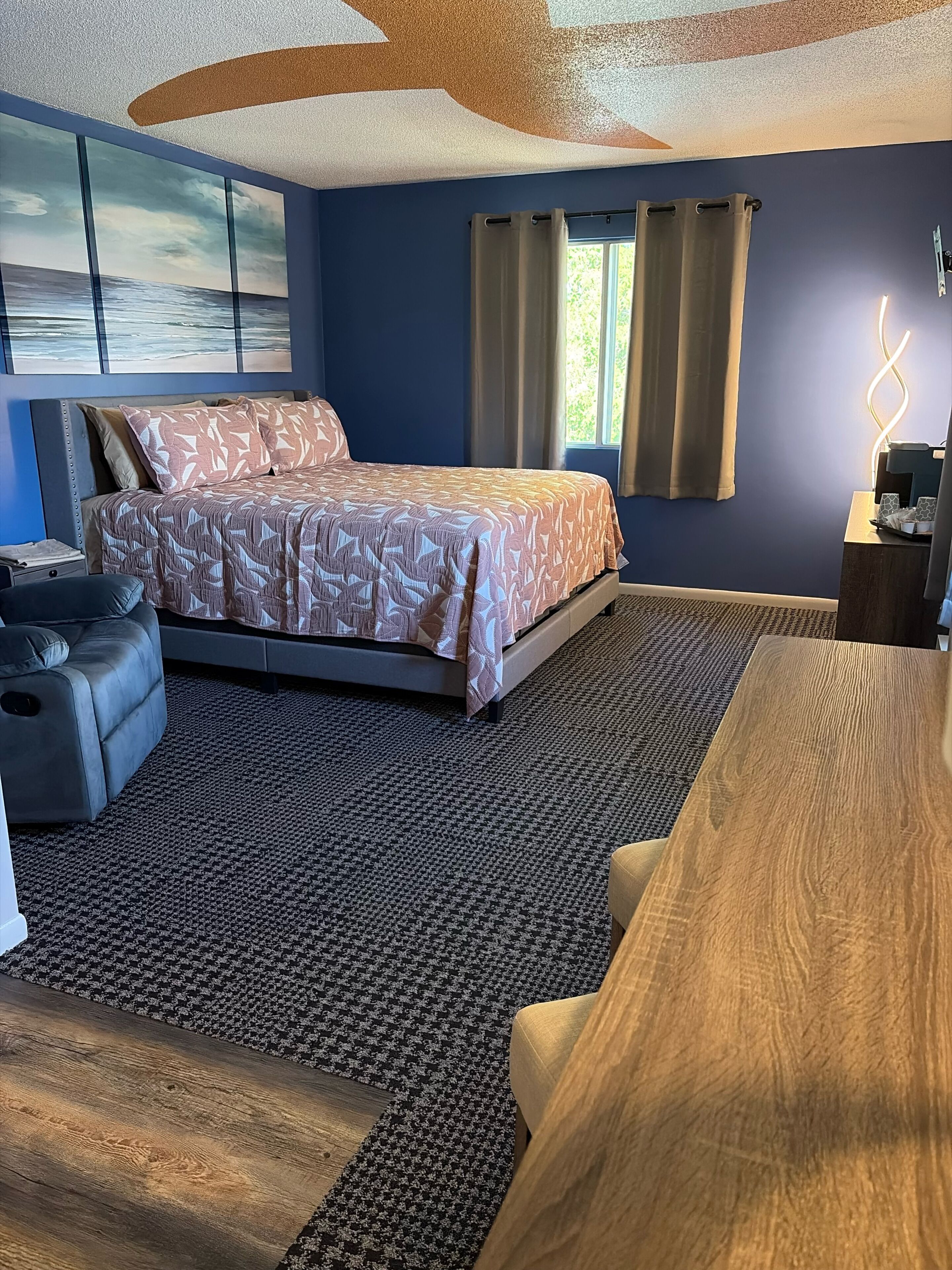 A bedroom with a bed, a sofa, a desk, and a view of the outdoors.