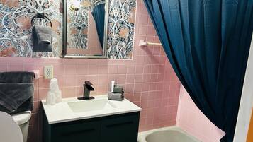 A bathroom with a sink, mirror, and bathtub.