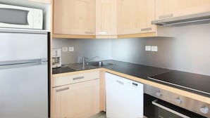 A kitchen with light wooden cabinets, a black countertop, a built-in microwave, a dishwasher, and a stainless steel range hood. - VVF Résidence Arcachon (Arcachon)