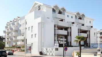A modern white building with multiple balconies and a sign indicating directions to Front de Mer and Embarcadero.