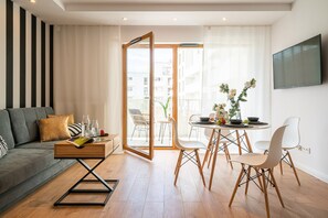 A modern living room with a sofa, a coffee table, and a dining area with chairs and a table.