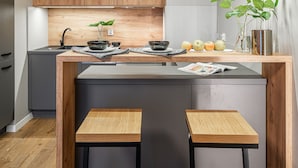 Eine moderne Küche mit Holzschränken, einer Kochinsel in der Mitte, zwei Barhocker und einem Spiegel darüber.