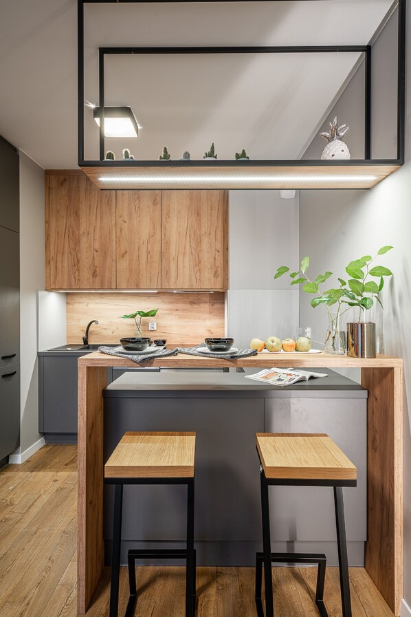 A modern kitchen with wooden cabinets, a central island, two stools, and a mirror above the island.