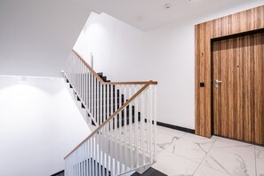 Ein modernes Interieur mit einer weißen Treppe, einer Holztür und einem Marmorboden.