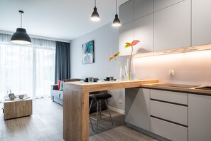 A modern kitchen with a wooden island, bar stools, and pendant lighting.