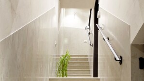 Un escalier en marbre, doté de rampes et orné d’une plante à son sommet.