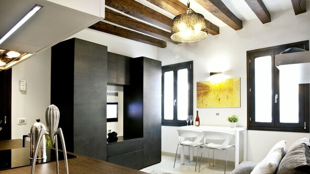 Une cuisine moderne avec des meubles de couleur sombre, un plan de travail en bois et un luminaire suspendu.