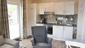 A modern kitchen with white cabinets, a black countertop, and a tiled backsplash. - Löwenstein Ferienwohnungen (Willingen)