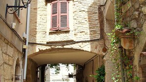 A narrow cobblestone alleyway with stone buildings, a wooden door, and a hanging lantern. - Hello Côte d'Azur - Spacious apartments at a 5 min walk from the beach (Antibes)
