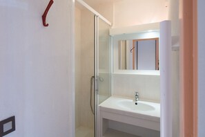 A bathroom with a glass shower enclosure, a white sink, and a mirror above the sink. - VVF Résidence Les Angles Pyrénées (Les Angles)