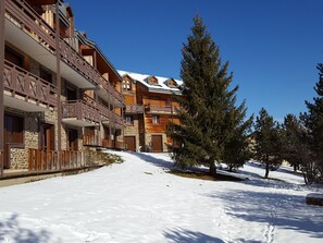 A snow-covered pathway leading to a multi-story building with balconies and wooden exterior. - VVF Résidence Les Angles Pyrénées (Les Angles)