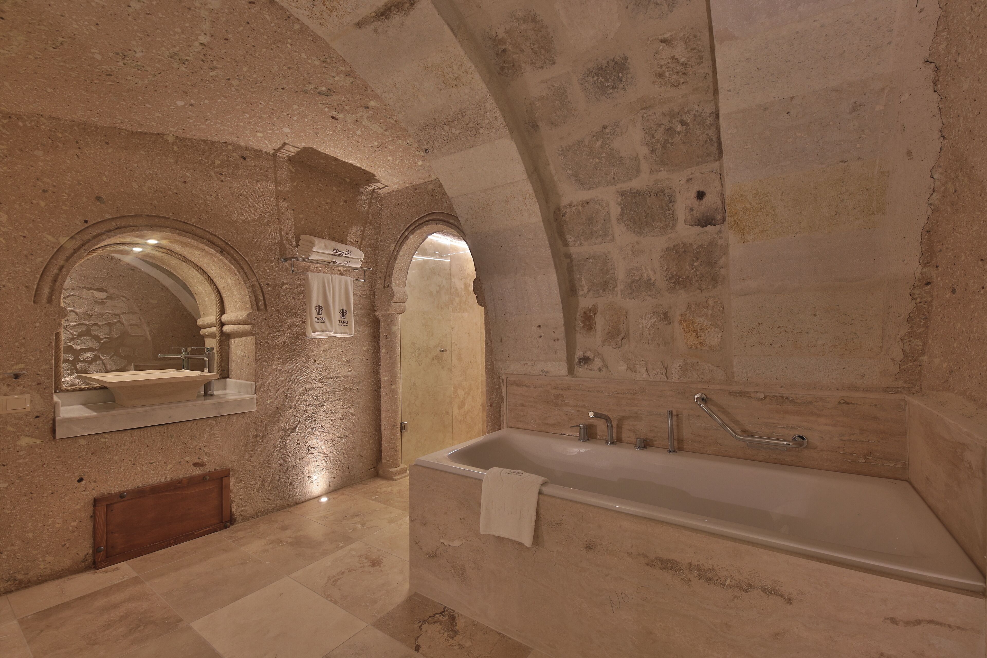 Un baño con pared de piedra, un lavamanos, un espejo y una bañera.