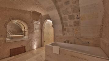 Un baño con pared de piedra, un lavamanos, un espejo y una bañera.