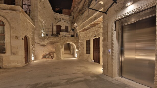 Un edificio de piedra con ascensor, arcos y una escalera.