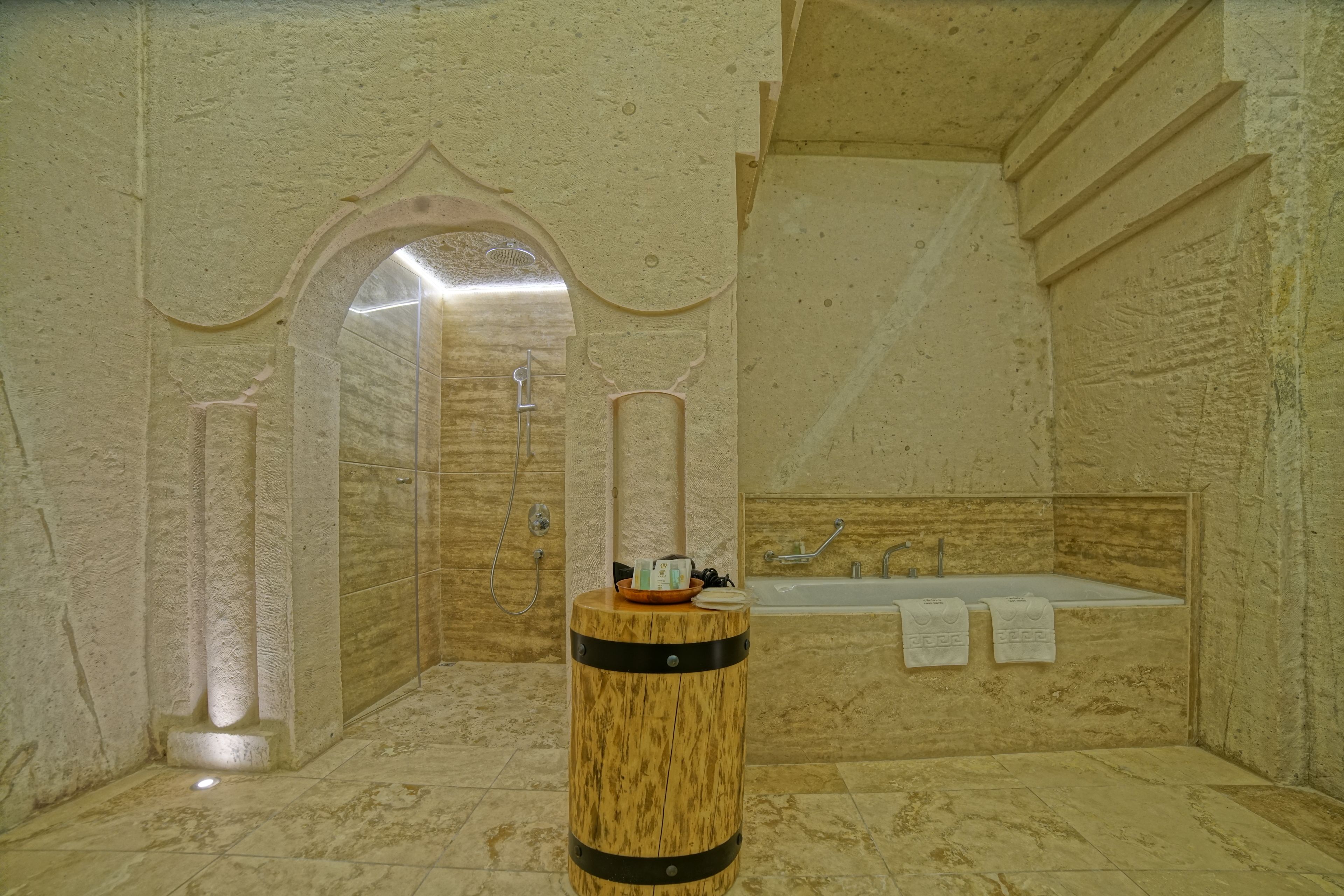 A bathroom with a bathtub, a wooden barrel stool, and a towel rack with towels.