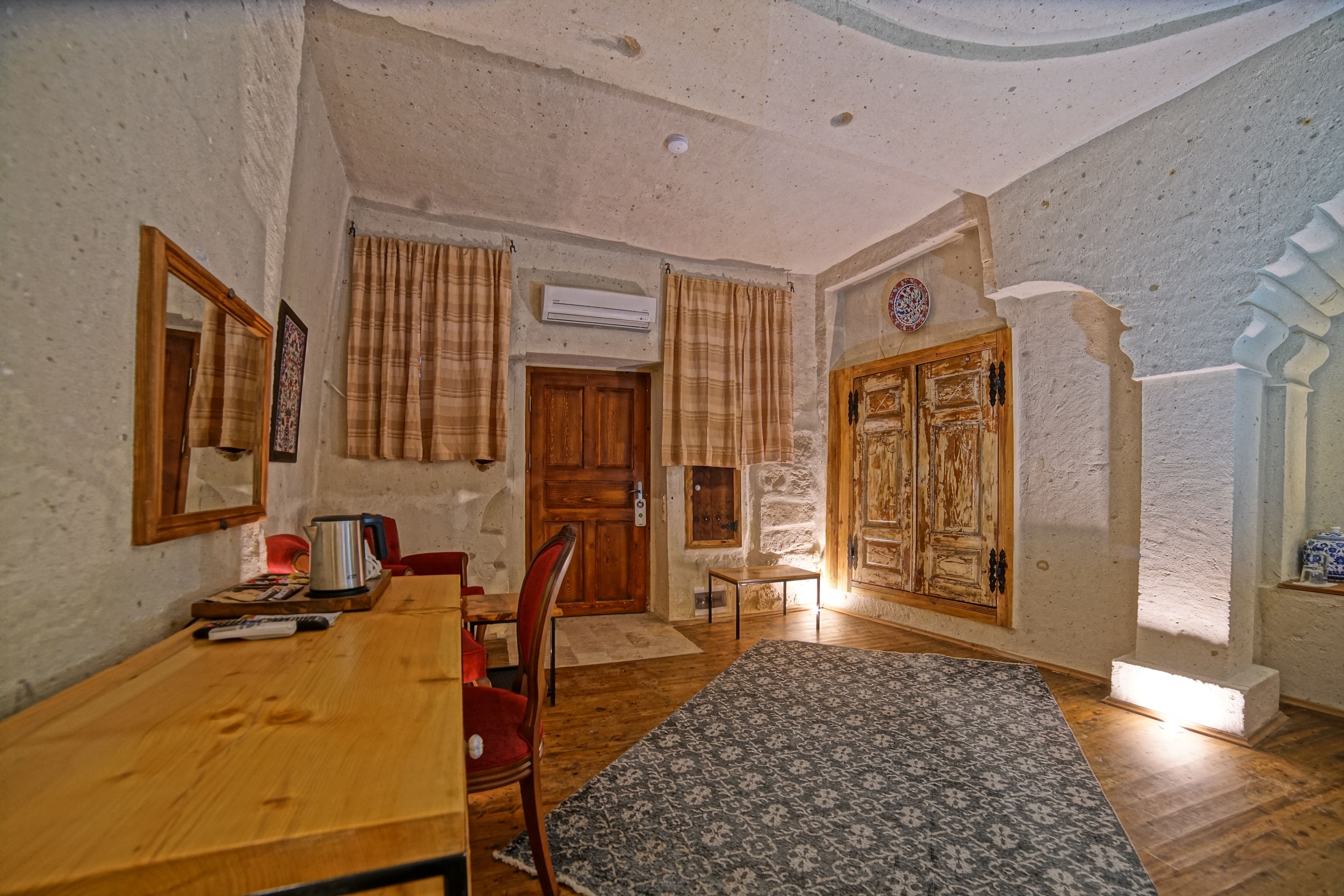 Una stanza con un tavolo e sedie in legno, un tappeto decorato e una porta in legno.