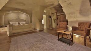 Una habitación amplia con una cama grande, una mesa de centro de madera y dos sillones.