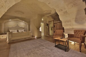 Una habitación amplia con una cama grande, una mesa de centro de madera y dos sillones.