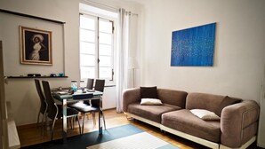 A modern living room with a sofa, dining table, chairs, and artwork on the walls. - Comoda Casa degli Indoratori (Genoa)