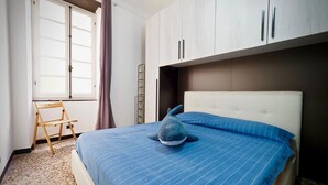 A bedroom with a bed, a window with curtains, and a wardrobe. - Comoda Casa degli Indoratori (Genoa)
