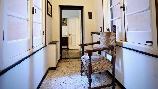 A narrow hallway with a wooden chair and a white refrigerator. - Comoda Casa degli Indoratori (Genoa)