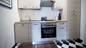 A compact kitchen with a gas stove, oven, and stainless steel cabinets. - Comoda Casa degli Indoratori (Genoa)