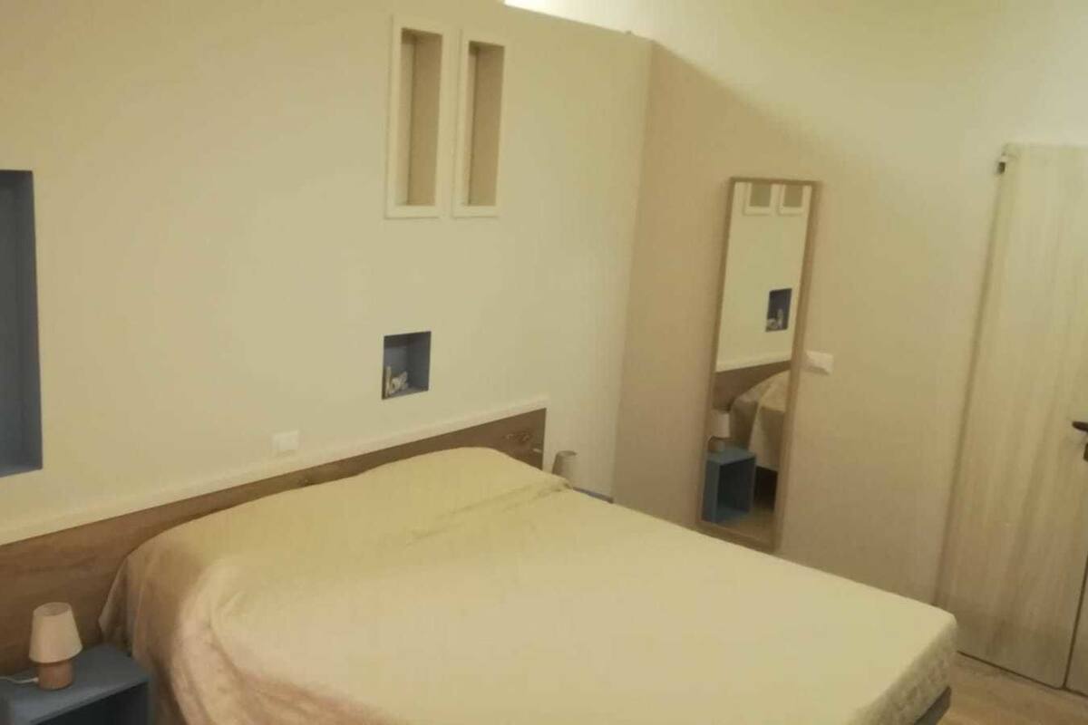 Una camera da letto con un letto, un comodino, uno specchio e un armadio.