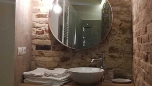 Un bany amb un mirall rodó, un rentaplat i un penjamantes.