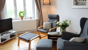 A living room with a television, two armchairs, a coffee table, and a floor lamp. - Urlaub Hamburg Altes Land (Hamburg)