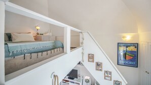 A bedroom with a bed, bedside table, lamp, and a framed picture on the wall. - Corricella Sea Window (Procida)