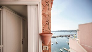 A view from a balcony overlooking a marina with boats, a clear sky, and a distant shoreline. - Corricella Sea Window (Procida)