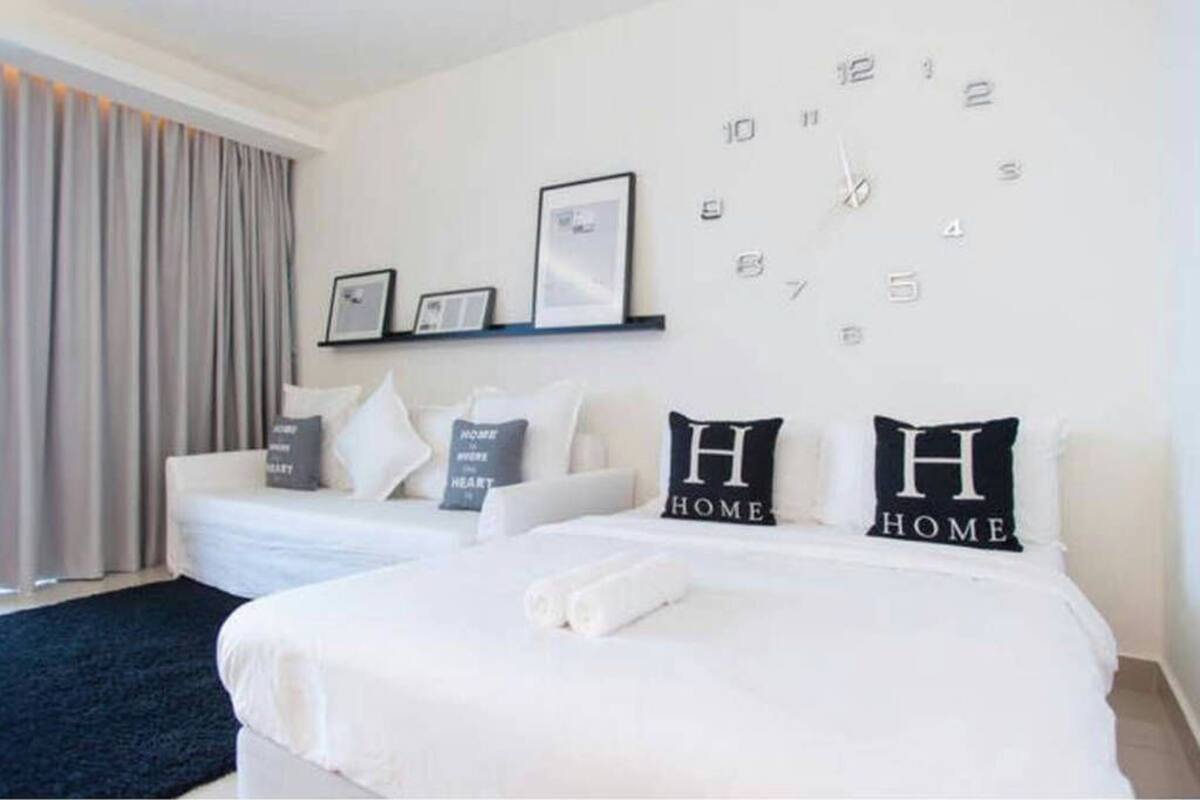 A hotel room with a bed, a sofa, a wall clock, and framed pictures.