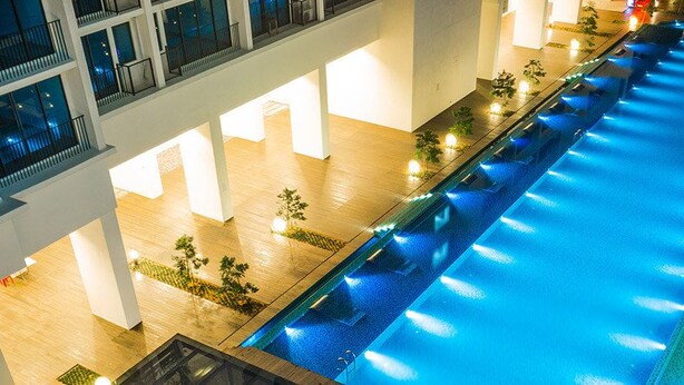A large indoor swimming pool with multiple levels of balconies and a wooden floor. - Miko's Home (Shah Alam)