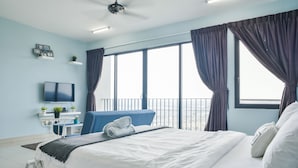 A modern hotel room with a large bed, a TV, a desk with a computer, and a balcony with curtains. - Miko's Home (Shah Alam)