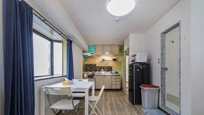 A compact kitchen with a dining area, a refrigerator, and a microwave. - Shinsaibashi Su Casa Apartment (Osaka)