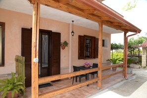 A covered outdoor seating area with a wooden bench, a table, and chairs. - B&B Valeri (Tropea)