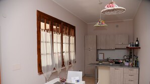 Una piccola cucina con zona pranzo, mobili in legno, un tavolo bianco e un lampadario.